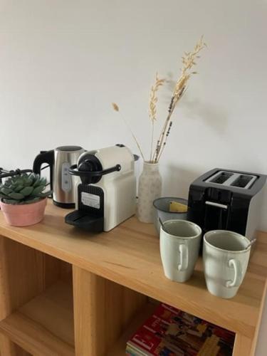 une étagère en bois avec une cafetière et des tasses dessus dans l'établissement Grande chambre indépendante, charme, calme sur jardin, Nantes centre, accès privé par escalier de l'immeuble, sdb & wc privés, 10 minutes gare et palais des congrès, à Nantes