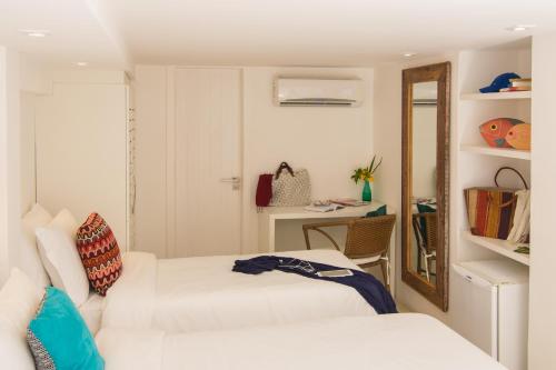 a white room with two beds and a mirror at La Chimère Buzios Essence in Búzios