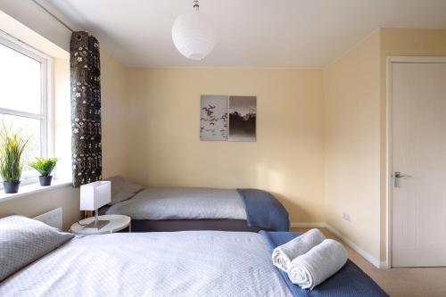 a bedroom with two beds and a window at Guildford Townhouse with Parking in Guildford