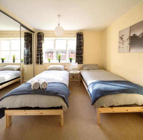 a bedroom with two beds and a mirror at Guildford Townhouse with Parking in Guildford