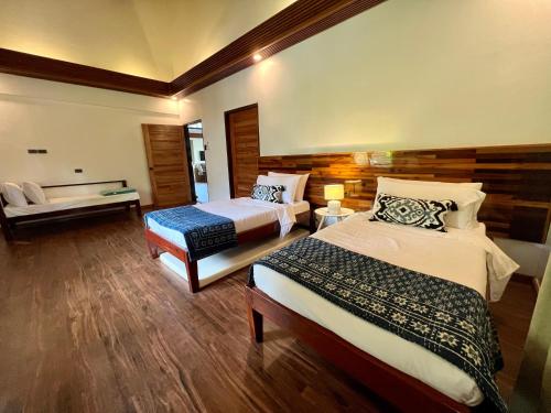 a hotel room with two beds and a bench at Sandy Feet Siargao in General Luna