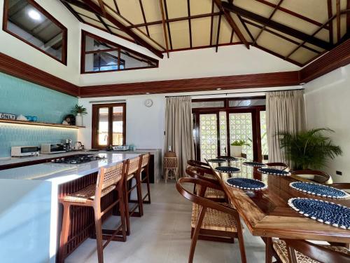 a kitchen with a long wooden table and chairs at Sandy Feet Siargao in General Luna