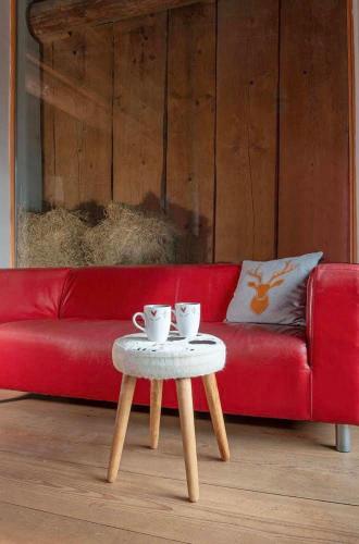 a red couch with a table with two cups on it at La Stalla in Vicosoprano
