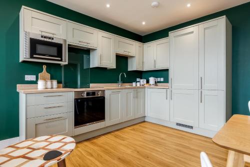 a kitchen with white cabinets and green walls at Tower House Apartments in Bournemouth