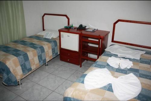 a room with two beds and a wooden dresser with two beds at Lagos Hotel in Catalão