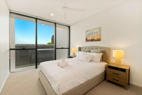 a bedroom with a large white bed and glass windows at Excellent location Luxury 2BR apt w carpark in Brisbane