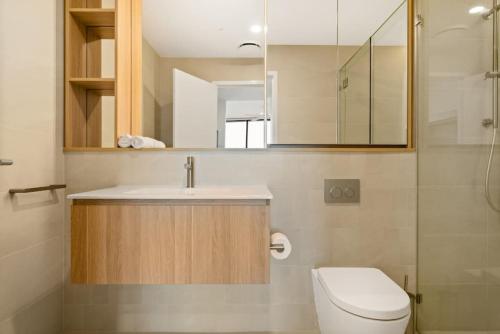 a bathroom with a toilet and a sink and a mirror at Excellent location Luxury 2BR apt w carpark in Brisbane