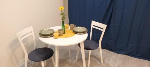 a white table and chairs with a vase with a flower at Central Cracow Apartments in Kraków
