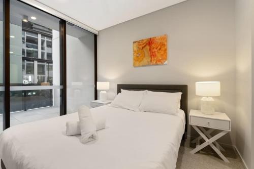 sypialnia z dużym białym łóżkiem i oknem w obiekcie 1BR Luxury apt at prime location w carpark w mieście Brisbane