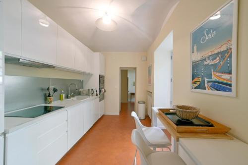 une cuisine avec des armoires blanches et une table en bois dans l'établissement Le Chapitre avec Jardin - Centre historique, à Nîmes