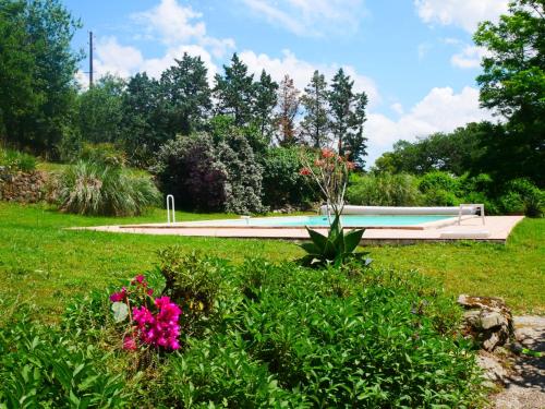 a bench in a park with flowers in the grass at Gite Les Volets Bleus du Segur in Le Ségur-Suech