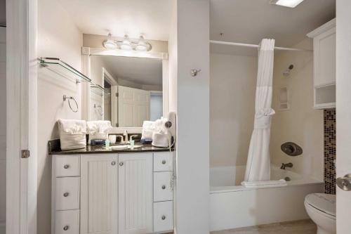 a bathroom with a sink and a toilet and a mirror at Luxury Beach Villa Wyndham Ocean Walk Resort in Daytona Beach