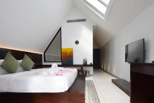 a bedroom with a white bed and a flat screen tv at Aborest Tropical Hostel in Siem Reap