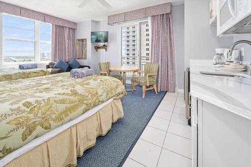 a hotel room with a bed and a table and a kitchen at Luxury 12th Floor 2 BR Condo Direct Oceanfront Wyndham Ocean Walk Resort Daytona Beach | 1201 in Daytona Beach