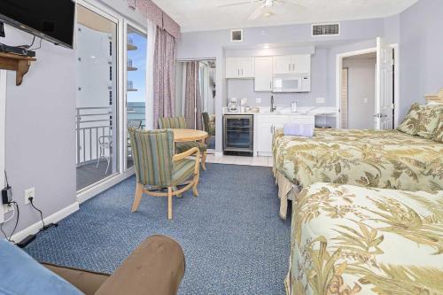 a bedroom with a bed and a table and a kitchen at Luxury 12th Floor 2 BR Condo Direct Oceanfront Wyndham Ocean Walk Resort Daytona Beach | 1201 in Daytona Beach