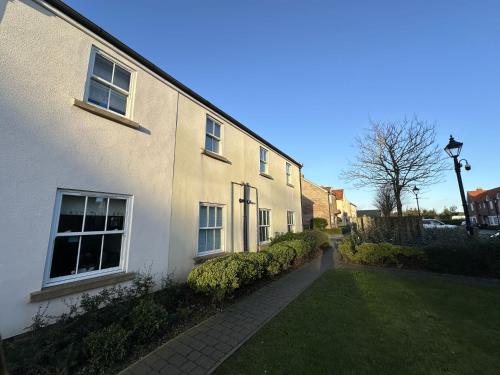 a white house with a sidewalk next to a yard at Starfish Shack - Part of the The Bay Filey Holiday Village with pool, gym and direct beach access, pub, restaurant, tennis and meadows walks in Filey