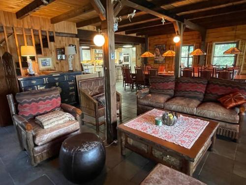 een woonkamer met banken en een tafel en stoelen bij Spectacular Seven Keys Camp on Pristine Loon Lake 