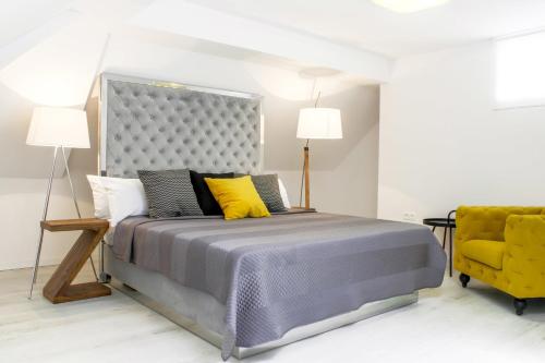 a bedroom with a bed and a yellow chair at Santa Cruz Apartments in Málaga