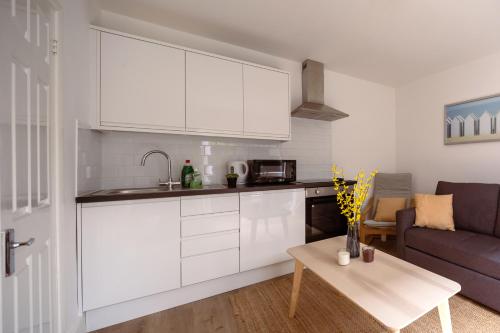 a kitchen with white cabinets and a living room at Guildford Town Centre with Parking in Guildford