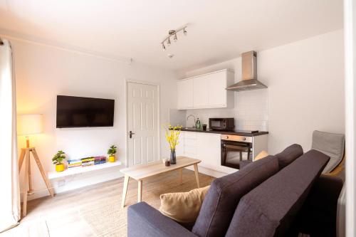 a living room with a couch and a kitchen at Guildford Town Centre with Parking in Guildford