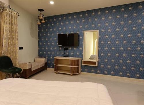 Schlafzimmer mit einem Bett, einem TV und einem Stuhl in der Unterkunft Hotel Ganesh Inn By BookingCare in Rewa