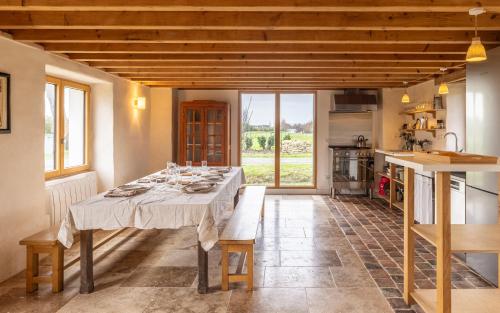 une salle à manger avec une table et une cuisine dans l'établissement Gîtes de Lézinadou - 14 personnes - Plomeur La Torche, à Plomeur