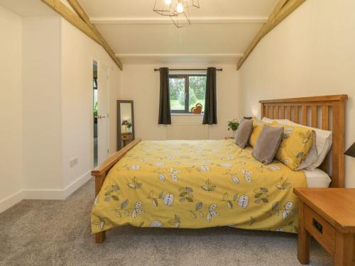 a bedroom with a bed with a yellow comforter at Windy Willows in Okehampton
