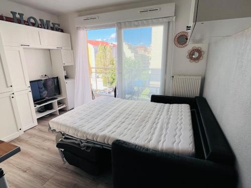 Studio terrasse et parking privé في نيس: غرفة نوم بسرير ابيض وتلفزيون