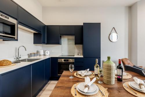 a kitchen with blue cabinets and a wooden table with wine glasses at Tower House Apartments in Bournemouth