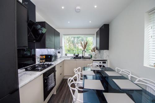 a kitchen with black cabinets and a table and chairs at Modern 4-Bed Retreat with Garden in Manchester