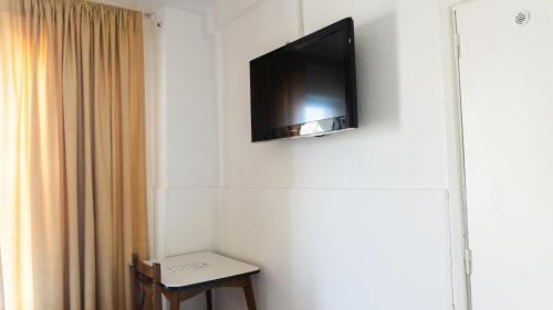 TV de pantalla plana colgada en la pared en Hotel Urbano Ventia en Comodoro Rivadavia