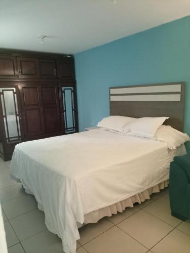 um quarto com uma grande cama branca e uma parede azul em Habitación cómoda em Villa Nueva