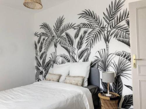 Schlafzimmer mit einem Bett und einem Wandbild von Palmen in der Unterkunft Résidence Appartements Niort wifi-parking in Niort