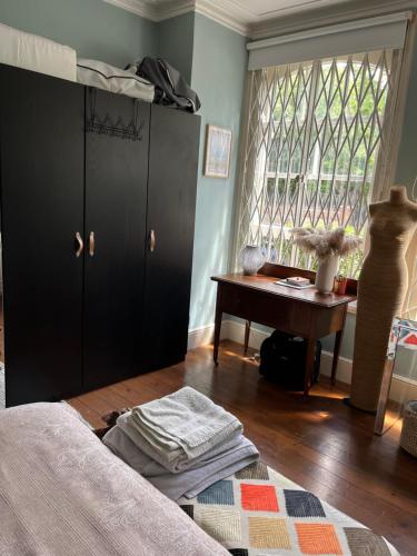 Schlafzimmer mit einem Bett, einem Schreibtisch und einem Fenster in der Unterkunft Dawn and Dudley the Sausage dog's Parkside Home in London