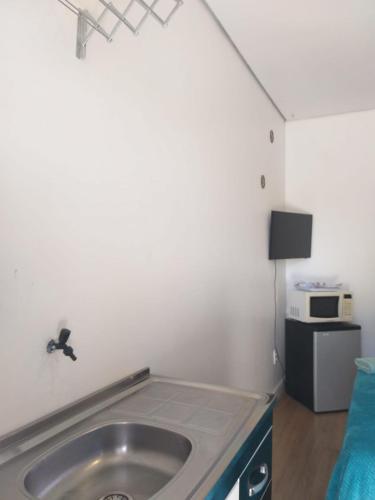 a bathroom with a sink and a microwave at Kitnet espaçosa e bem localizada - Próximo ao lago e centro de eventos in Cascavel