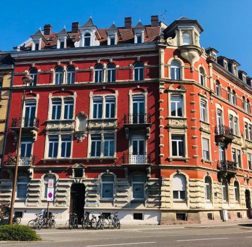 un grand bâtiment rouge avec des vélos garés à l'extérieur. dans l'établissement 4 étoiles Magnifique Neustadt - Spacieux, Central & Élégant avec balcon et belle vue, à Strasbourg