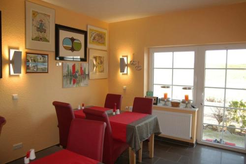 a dining room with a table and red chairs at Gäste-Zimmer am Elberadweg in Damnatz