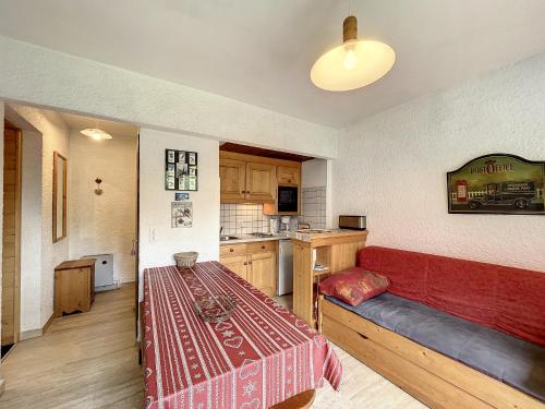 une chambre avec un canapé rouge et une cuisine dans l'établissement Appartement cosy au pied des pistes à Combloux avec balcon et casier à skis - FR-1-560-61, à Combloux