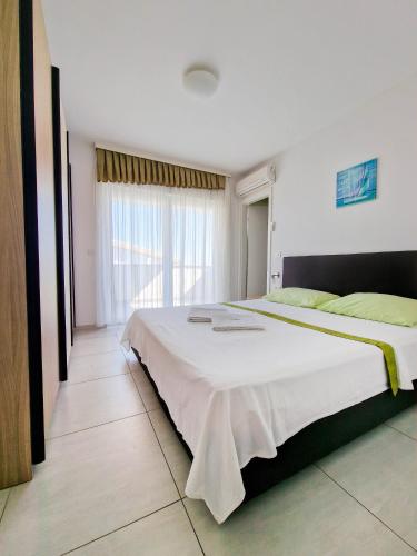 a large bed in a room with a large window at Vila Novak in Novalja