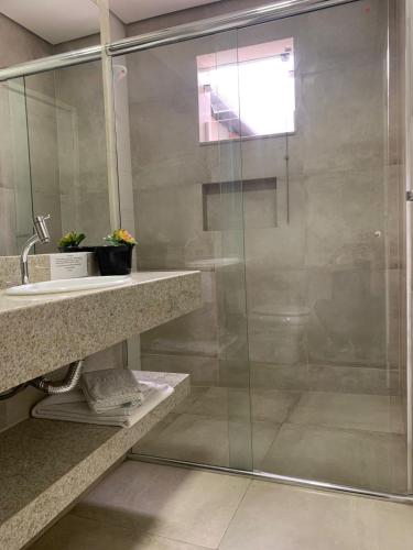 a bathroom with a glass shower and a sink at Hotel Ouro Verde in Três Pontas