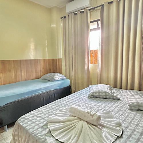2 camas individuales en una habitación con ventana en Hotel Económico, en Campo Grande