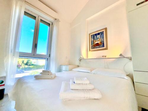 a bedroom with a white bed with towels on it at Villa Poetto Beach by Home and Experience , Cagliari, Poetto in Cagliari