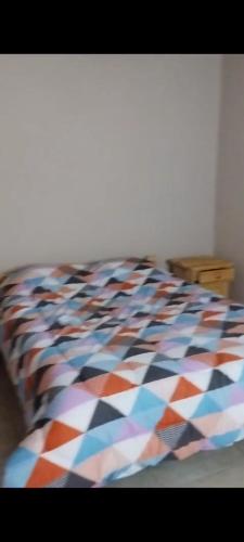 a bed with a multicolored comforter on it at Cabaña Dina in Santa Rosa del Conlara