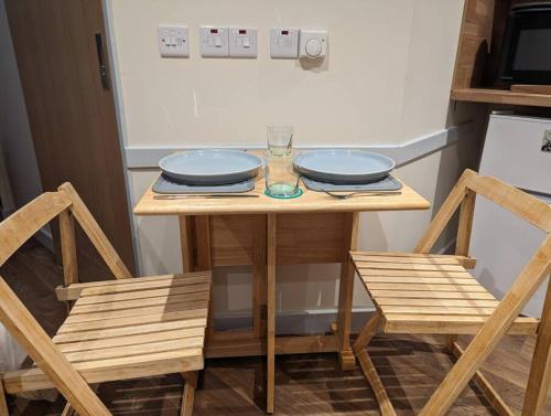 a wooden table with two plates and two chairs at The Coo Shed in Inverness