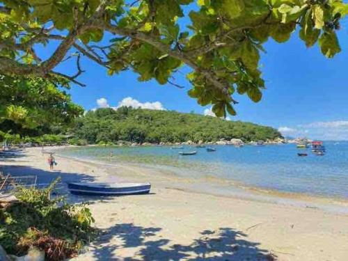 a beach with boats in the water and trees at Caminho do Mar Ap 4 in Governador Celso Ramos