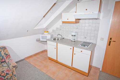 a kitchen with white cabinets and a sink at Seevilla Wochinz in Faak am See