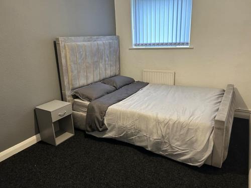 a bedroom with a bed with a night stand and a window at Two bedroom apartment room 18 in Stockton-on-Tees