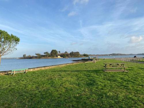 Deux tables de pique-nique dans l'herbe près d'une masse d'eau dans l'établissement Jolie maison rénovée au bord de la Ria, Belz, à Belz