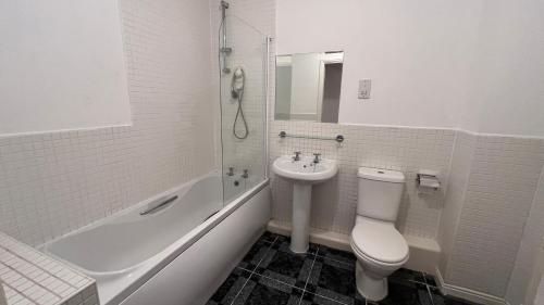 a white bathroom with a toilet and a sink at Maple Apartments in Stanley