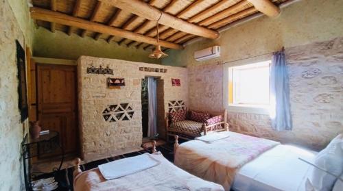1 Schlafzimmer mit 2 Betten, einem Fenster und einem Stuhl in der Unterkunft Kasbah Dar Talouste in Afela nʼIsly